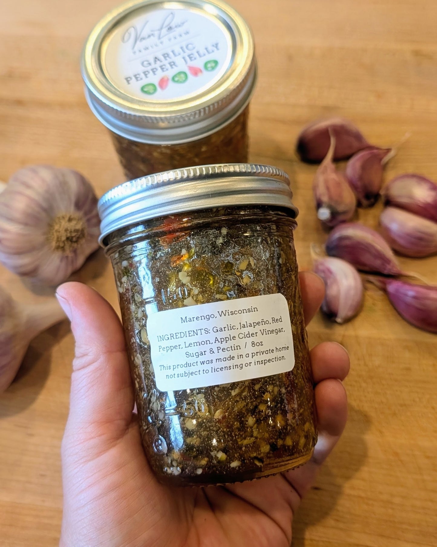 Hand holding garlic pepper jelly jar showing ingredients label